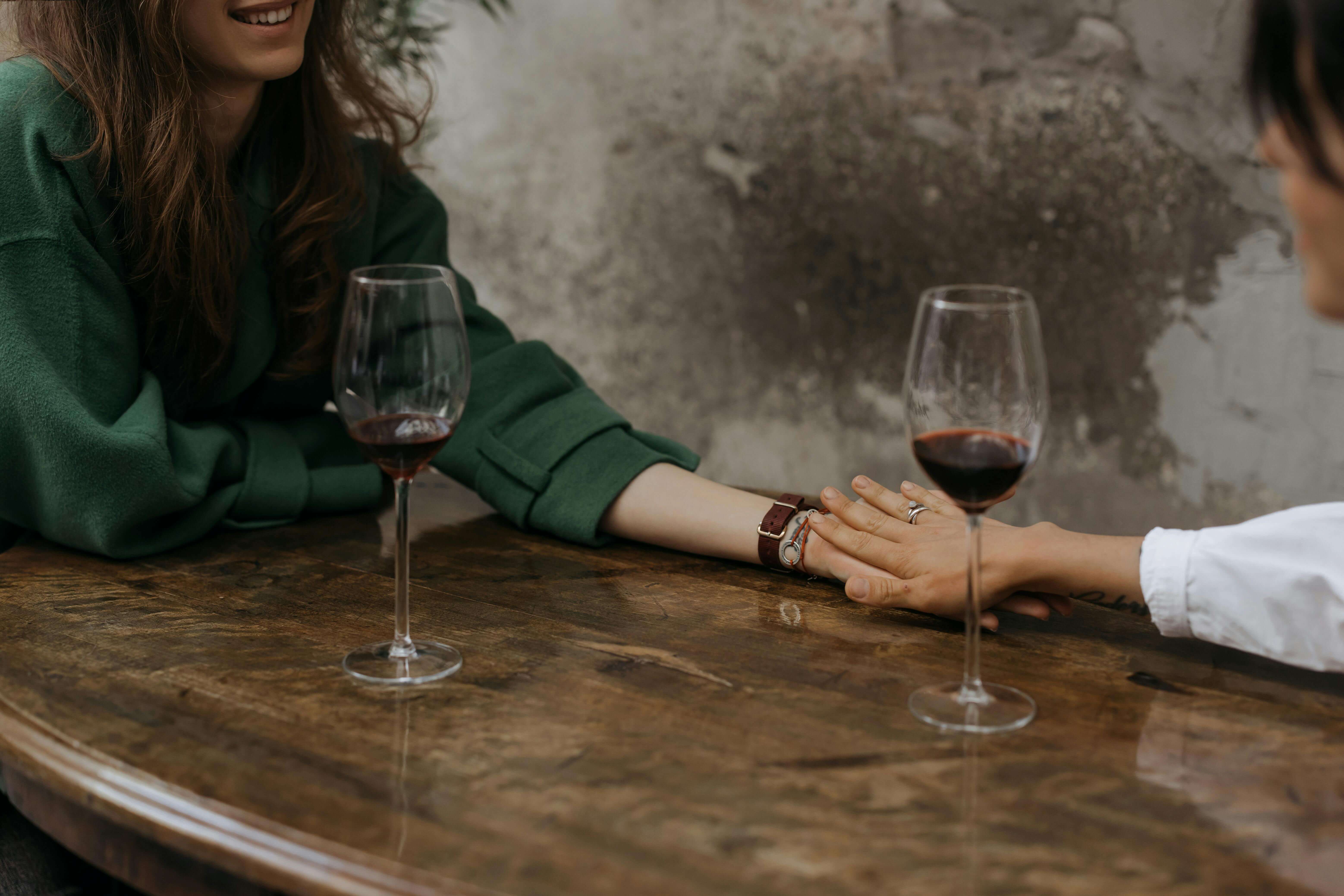 An escort and a client on a date holding hands across a table